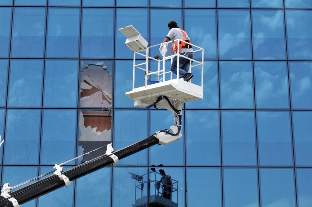 Glassplus worker fixing smashed glass on a large commercial building using a stair lift.